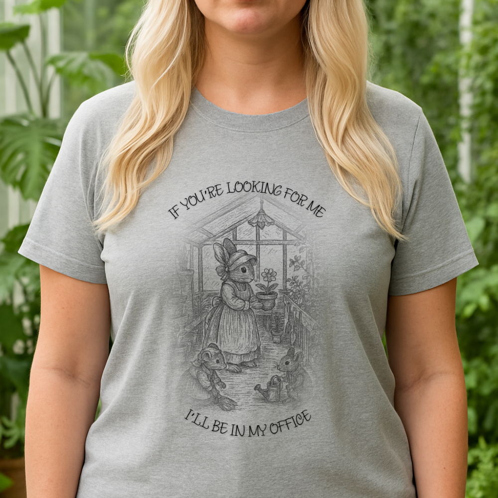 Platinum blonde woman wearing a loose-fitting athletic gray Bella Canvas 6400 T-shirt and black yoga pants, standing in front of a greenhouse. T-shirt is blank for custom design placement. Image shows her from the chin down with long layered hair.