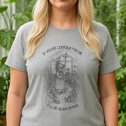 Platinum blonde woman wearing a loose-fitting athletic gray Bella Canvas 6400 T-shirt and black yoga pants, standing in front of a greenhouse. T-shirt is blank for custom design placement. Image shows her from the chin down with long layered hair.